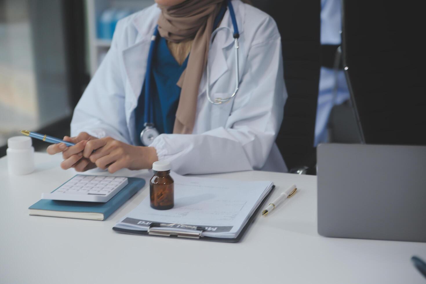 asiático psicólogo mujer señalando en pastillas botella a explicando medicina y prescripción a hembra paciente mientras dando asesoramiento acerca de médico y mental salud terapia a hembra paciente en clínica. foto