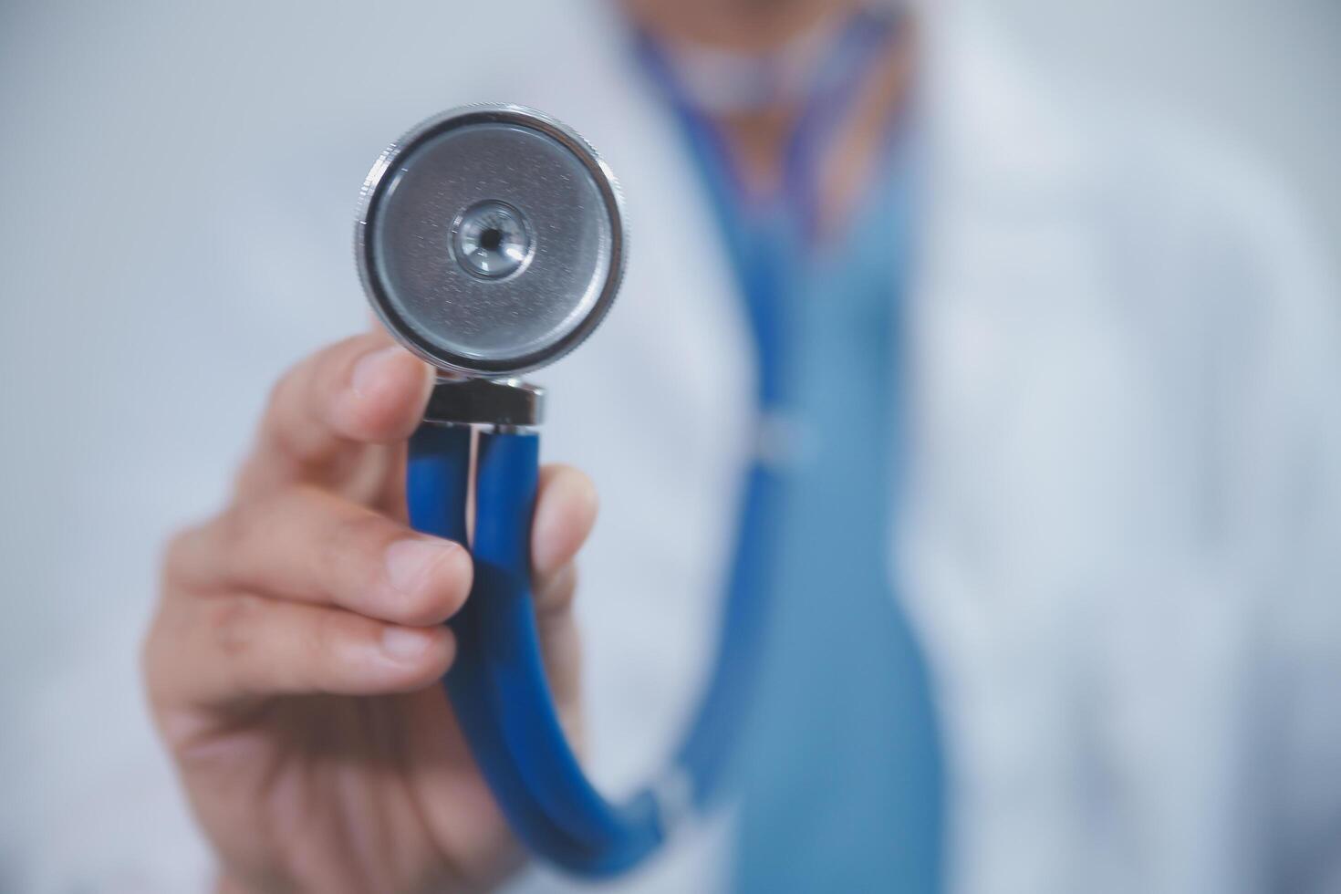 Senior doctor wearing white coat standing holding stethoscope in hands. Older male physician healthcare professional showing medical equipment ready to listen lungs or heart concept. Close up view photo
