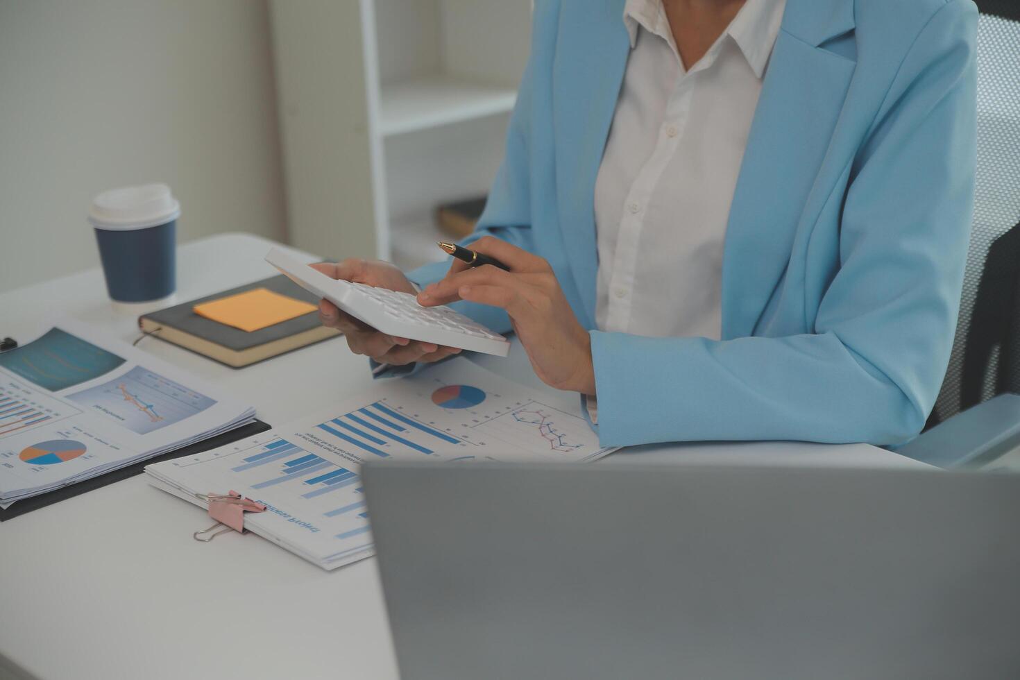 Charming Young asian businesswoman sitting on laptop computer in the office, making report calculating balance Internal Revenue Service checking document. photo