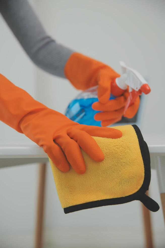 Woman cleaning table using rag and diffuser at home. photo