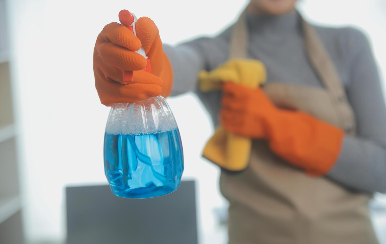 Woman cleaning table using rag and diffuser at home. photo