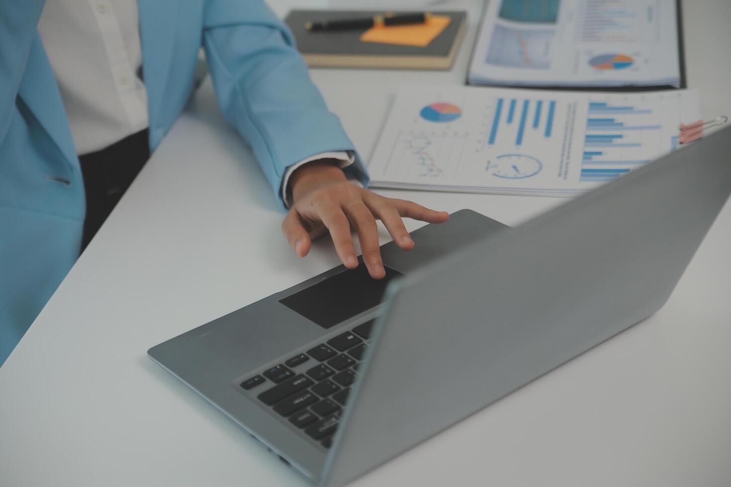 Charming Young asian businesswoman sitting on laptop computer in the office, making report calculating balance Internal Revenue Service checking document. photo