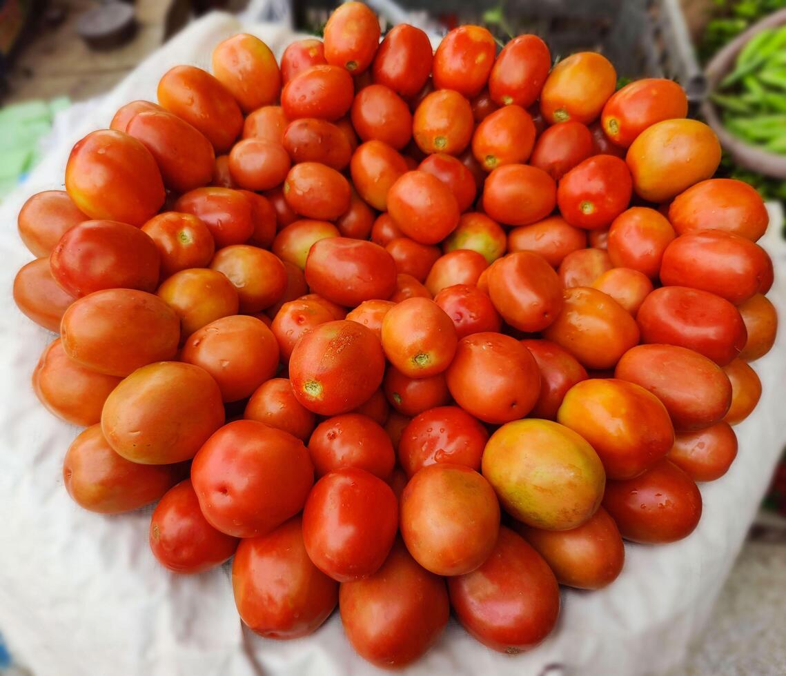 Tomatoes lying on a pile on top of each other, tomato texture. Group of fresh tomatoes. Tomato pattern. photo