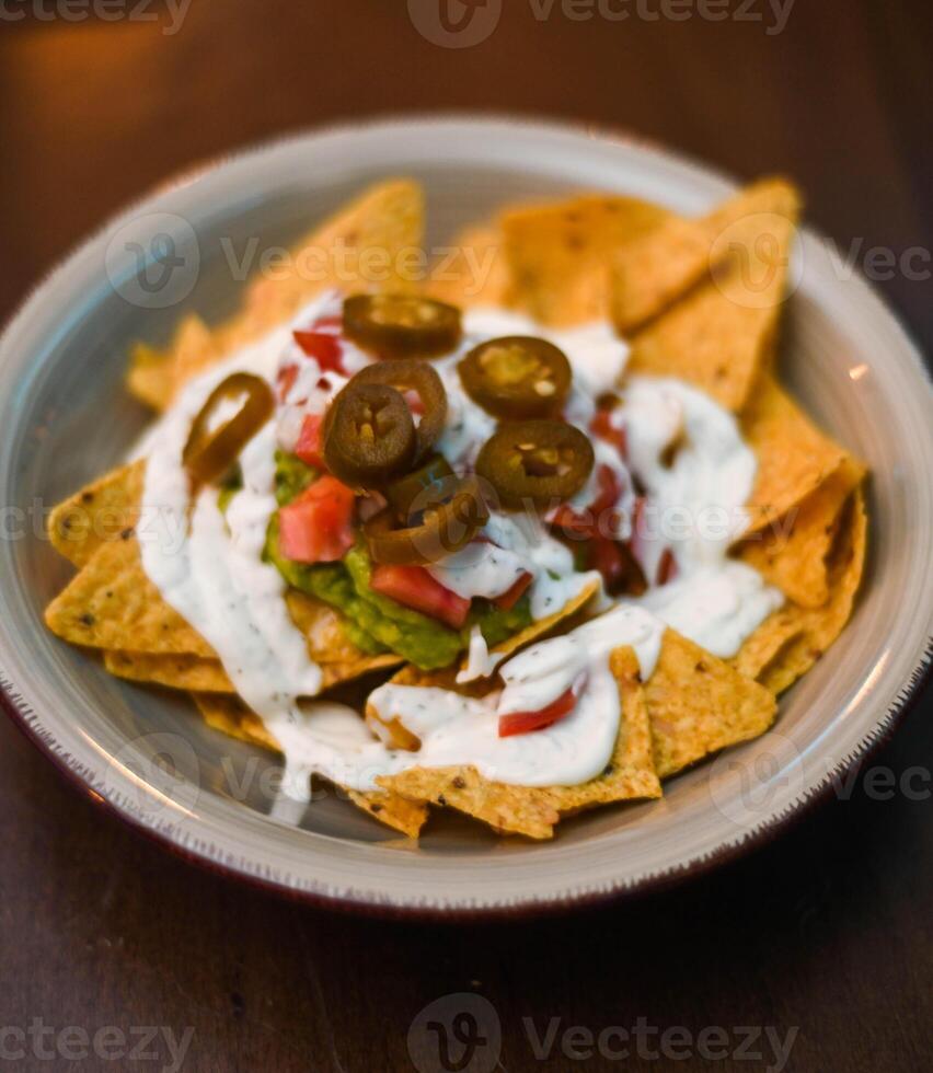 Serving of nachos with white sauce and jalapenos photo