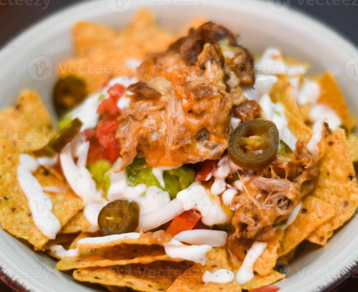 Serving of nachos with meat, cheese, white sauce and jalapenos photo