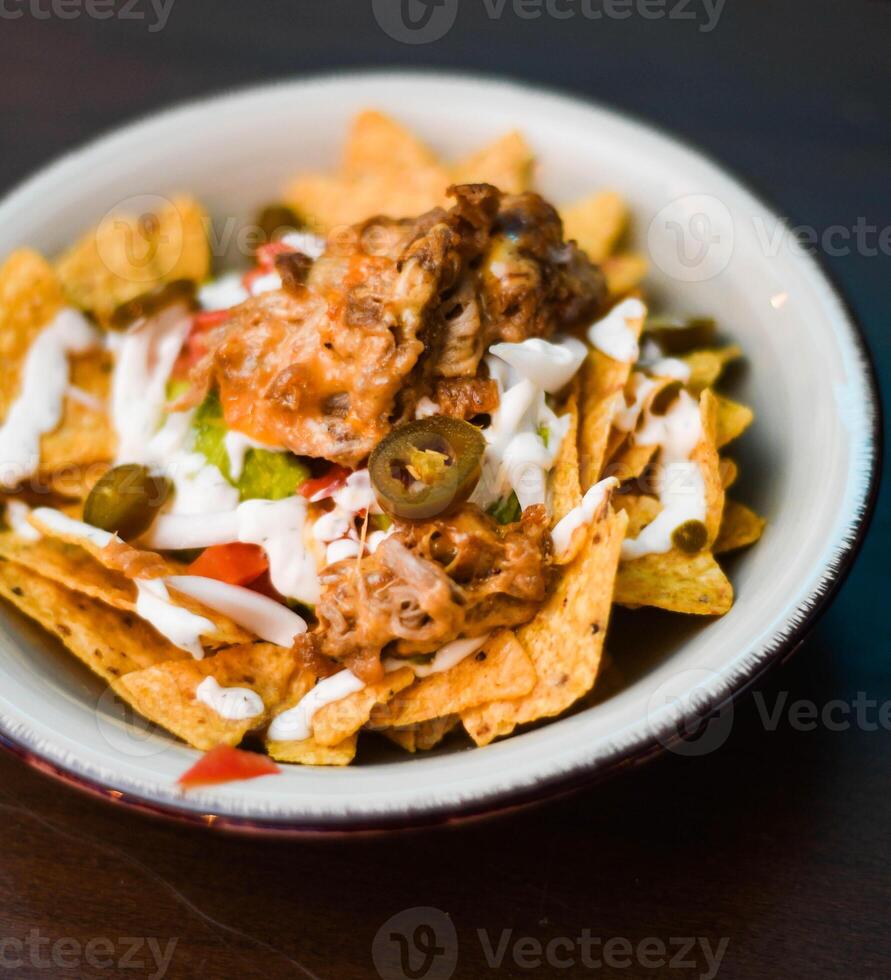 Serving of nachos with meat, cheese, white sauce and jalapenos photo