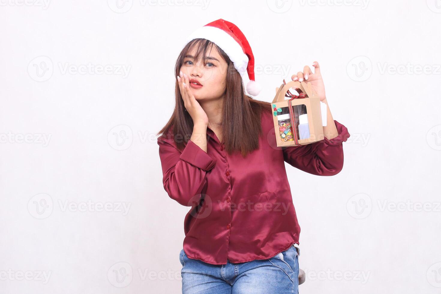 beautiful young southeast asian woman frowning hand number 5 sign carrying gift hamper in christmas wearing santa claus hat modern red shirt outfit white background for promotion and advertising photo