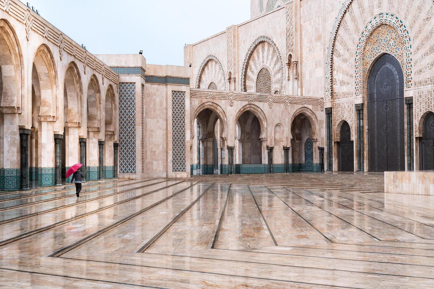 Casablanca, Morocco -march 25, 2024-person with red umbrella walks in Hassan II mosque during a rainy day photo
