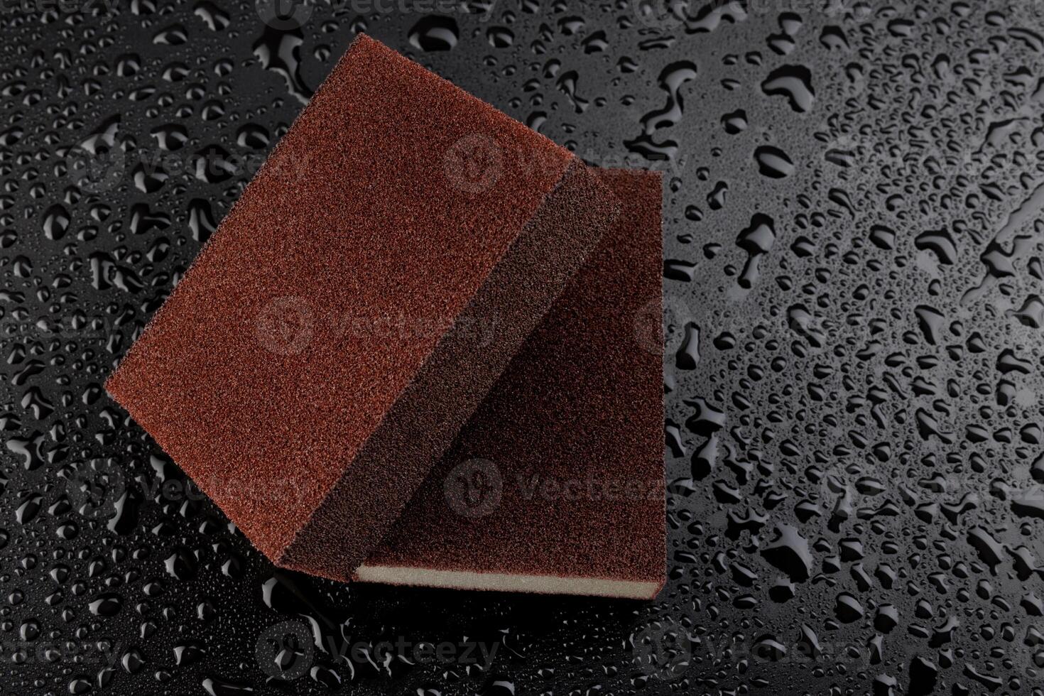 Melamine sponge on a black wet background. Beautiful drops of water around a melamine sponge. photo