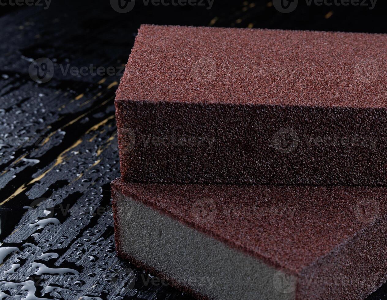 Melamine sponge on a black wet background. Beautiful drops of water around a melamine sponge. photo