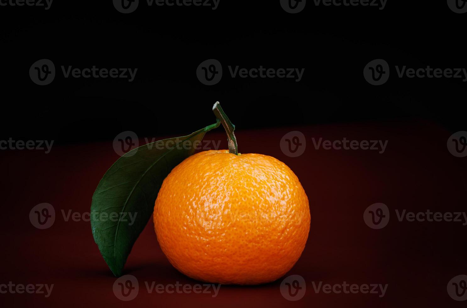 Two ripe juicy tangerines on a dark red background. photo