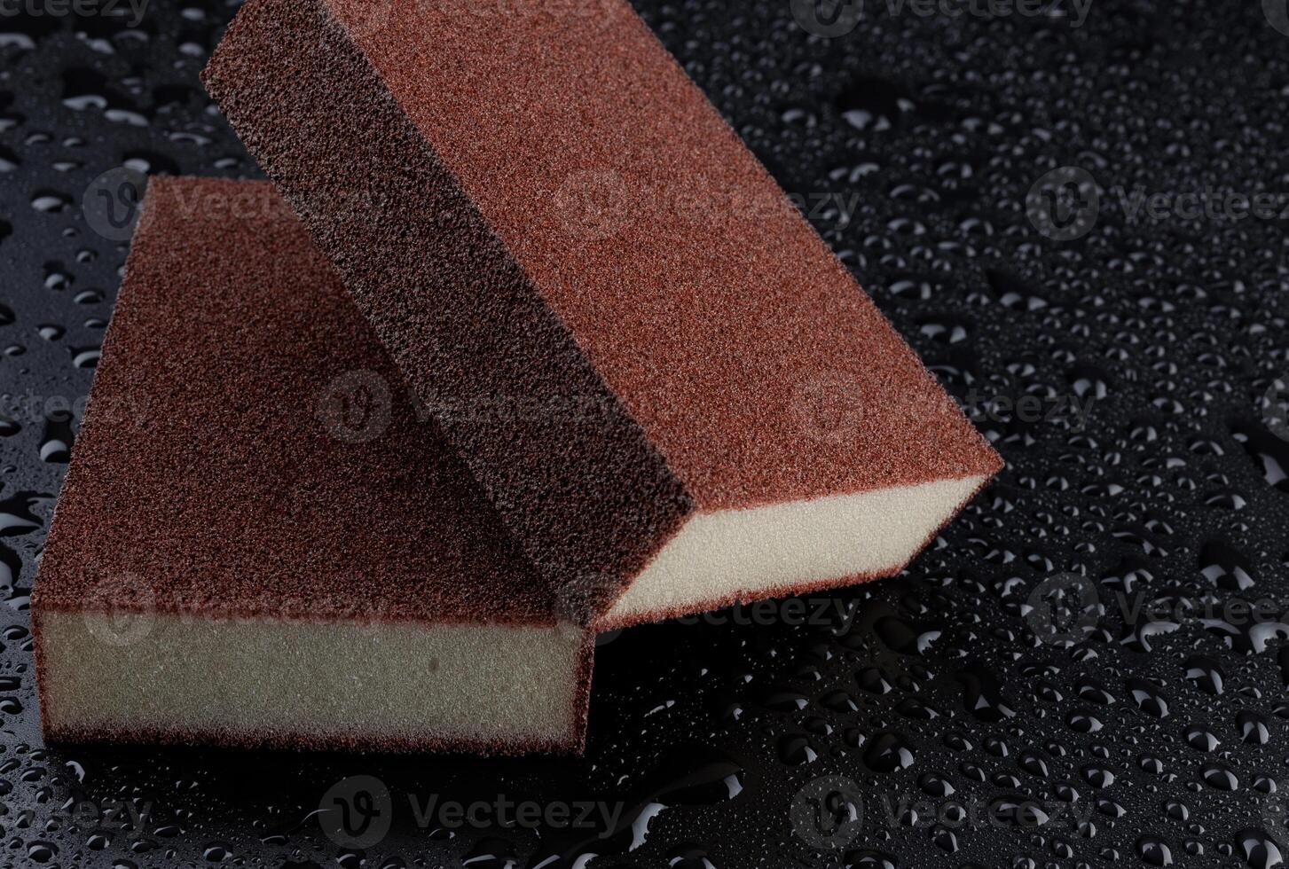 Melamine sponge on a black wet background. Beautiful drops of water around a melamine sponge. photo