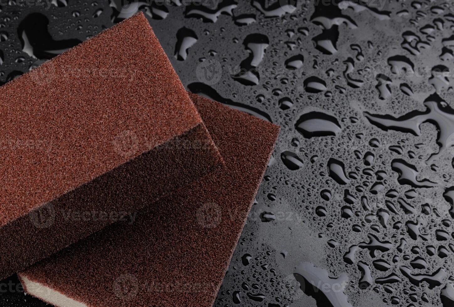 Melamine sponge on a black wet background. Beautiful drops of water around a melamine sponge. photo