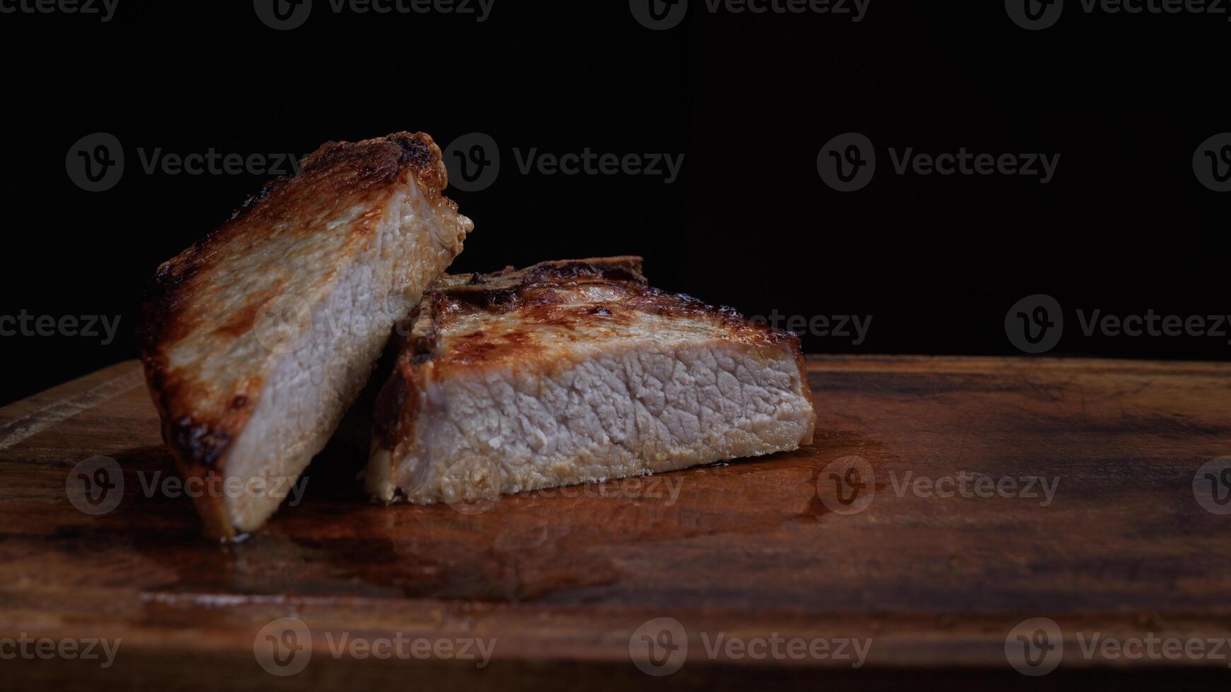 Roasted pork entrecote cut into pieces on a wooden cutting board. Grilled pork entrecote. Pork steak. photo