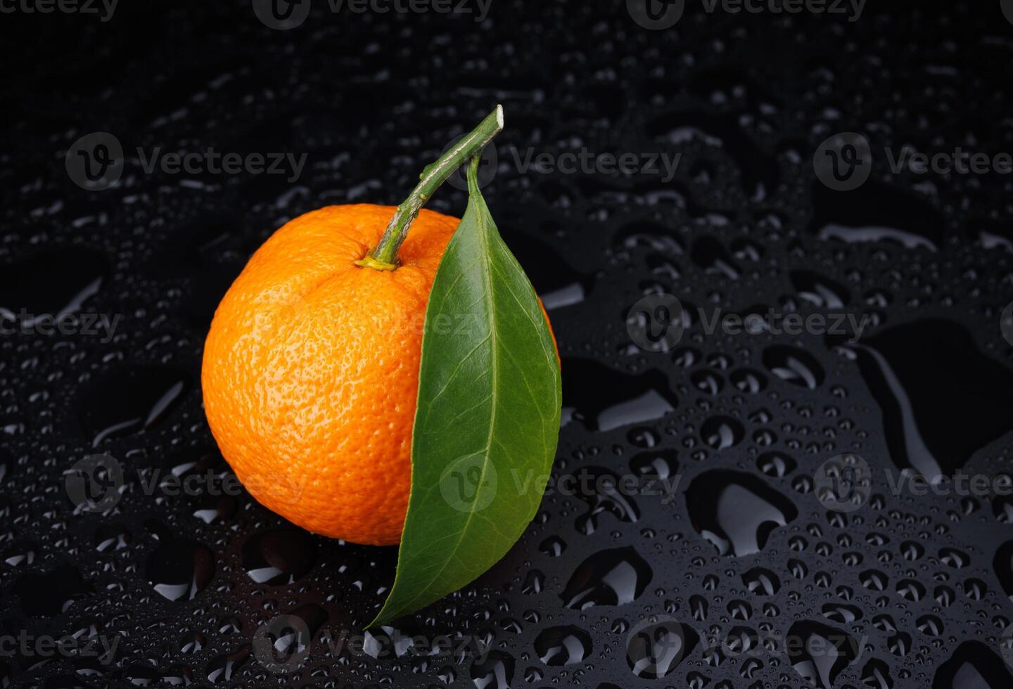 Ripe juicy tangerine on a black background with water drops. photo