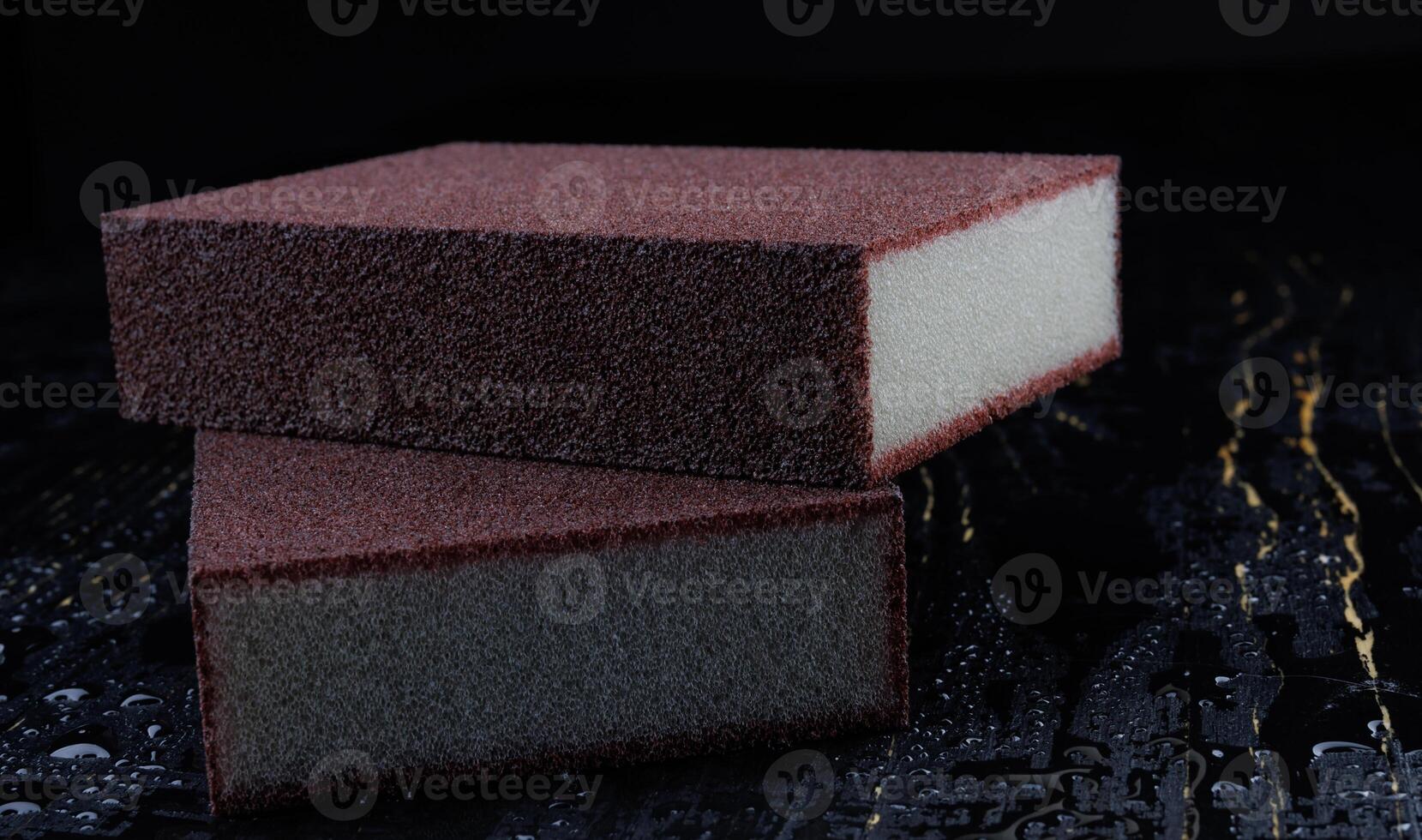 Melamine sponge on a black wet background. Beautiful drops of water around a melamine sponge. photo