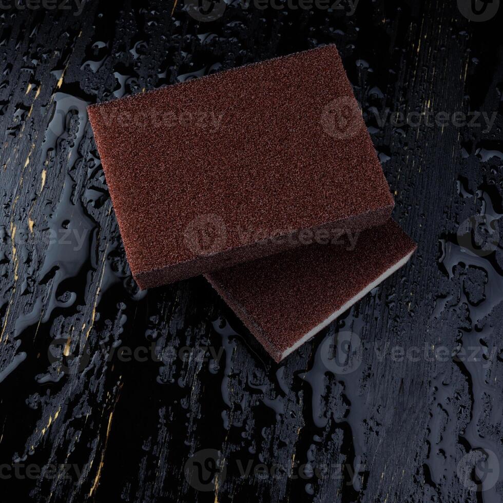 Melamine sponge on a black wet background. Beautiful drops of water around a melamine sponge. photo