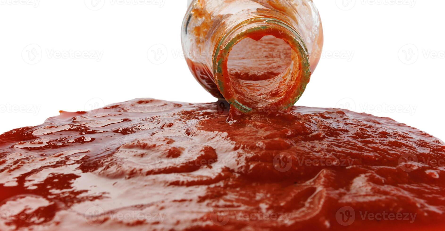 Tomato sauce . A glass bottle with ketchup and a puddle of ketchup spilled around it. photo