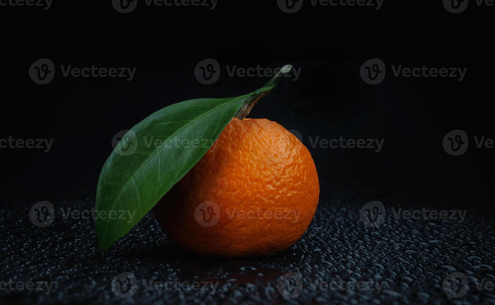 Ripe juicy tangerine on a black background with water drops. photo