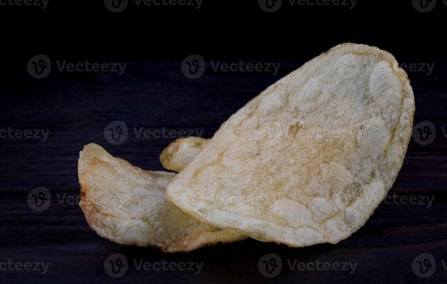 Potato chips on a dark background. Chips on a wooden board photo