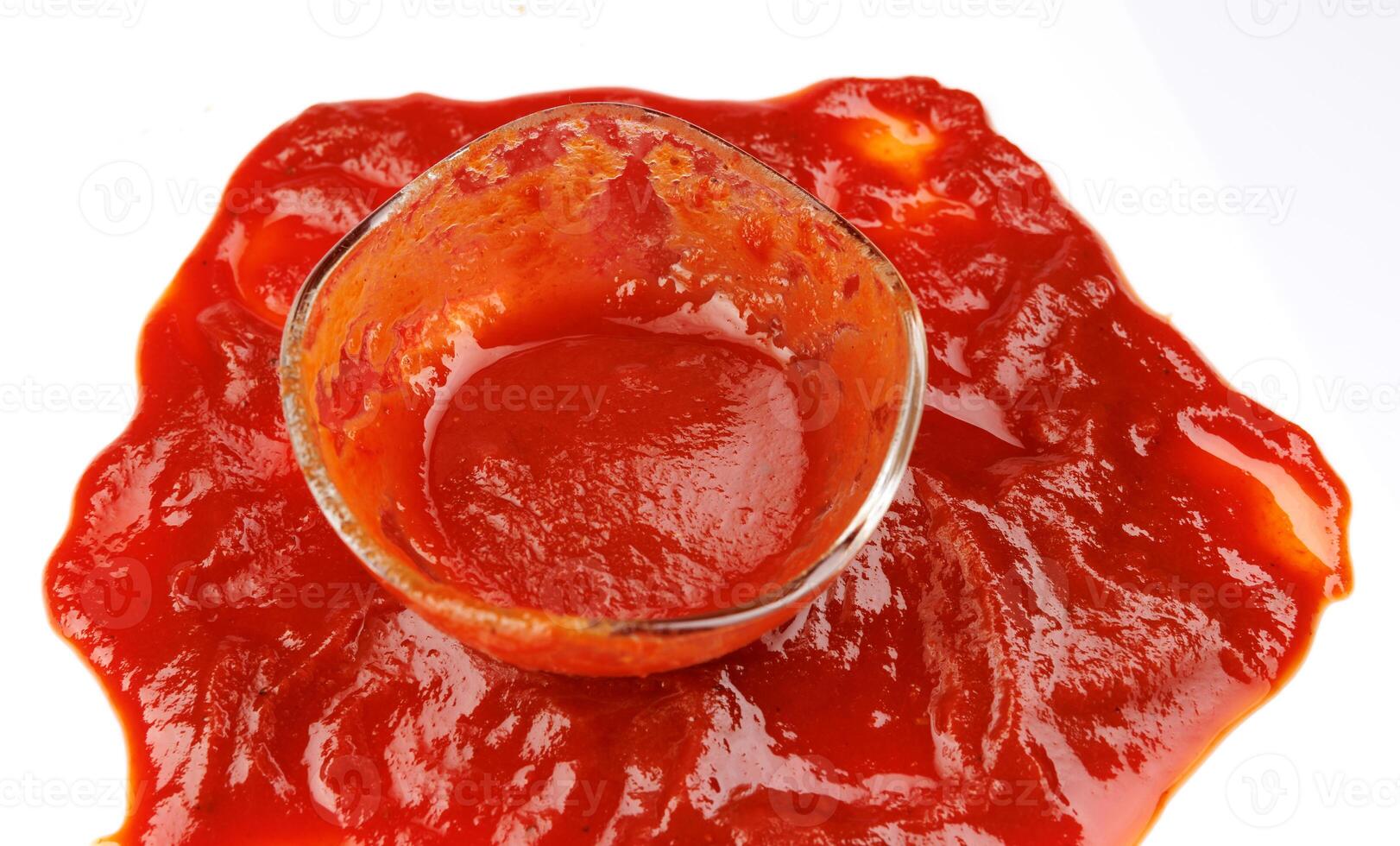 Tomato sauce . Glass cup with remaining ketchup and ketchup spilled around it. photo