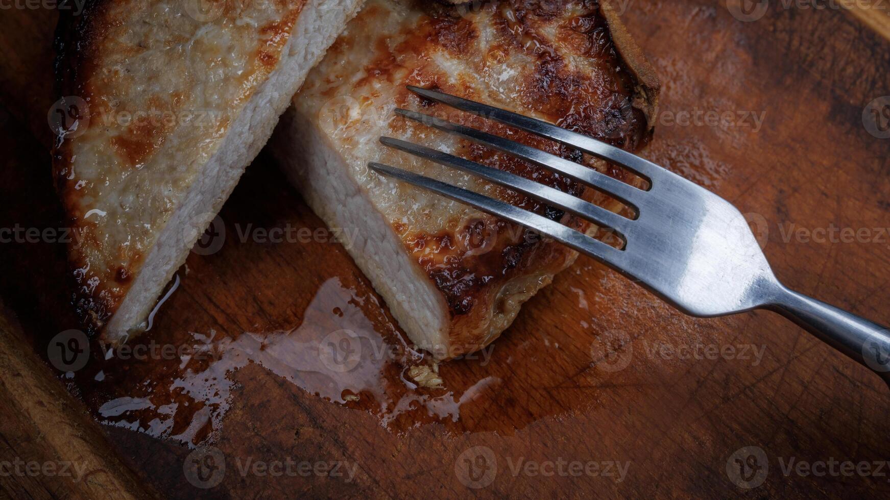 Roasted pork entrecote cut into pieces on a wooden cutting board. Fork in meat. photo