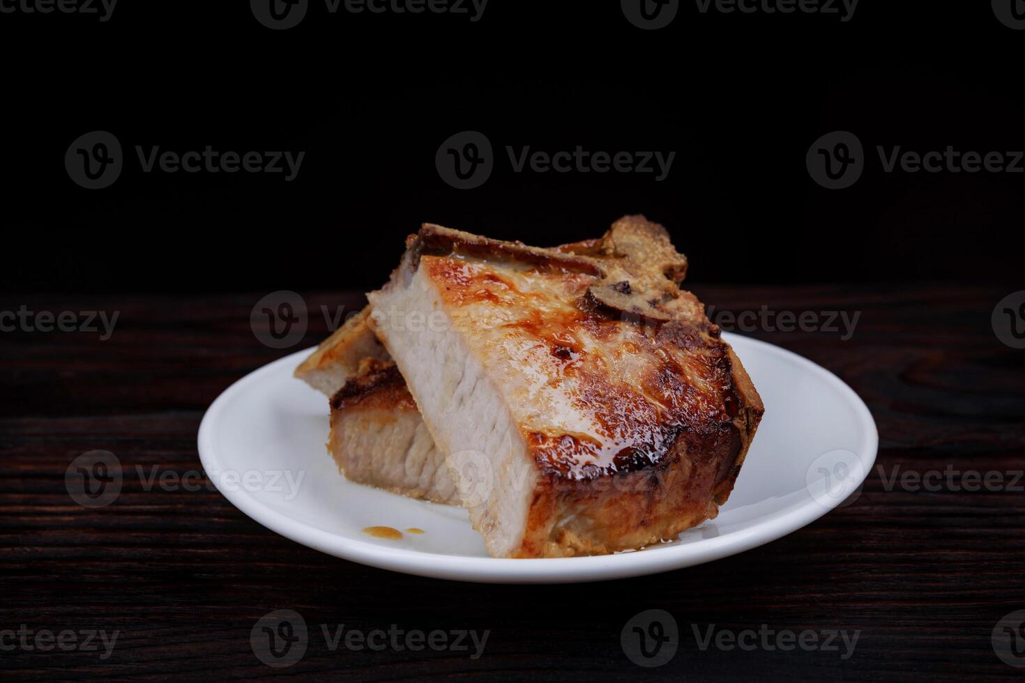 Roasted pork entrecote cut into pieces in a white plate on a wooden cutting board . Grilled pork entrecote. Pork steak. photo