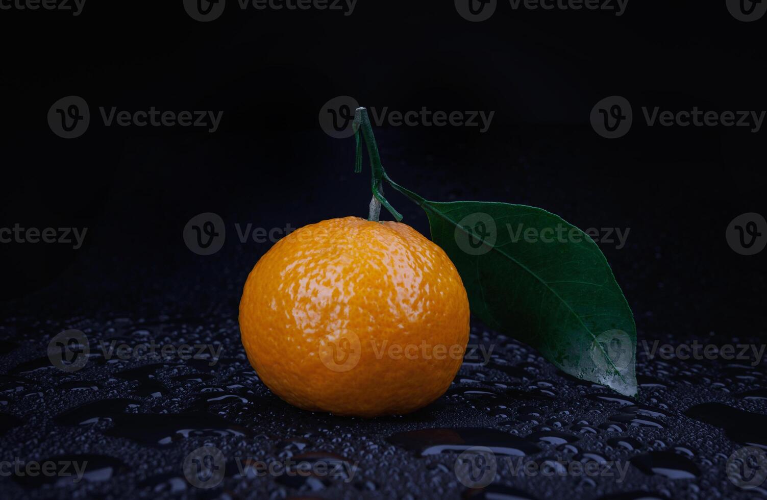 Ripe juicy tangerine on a black background with water drops. photo