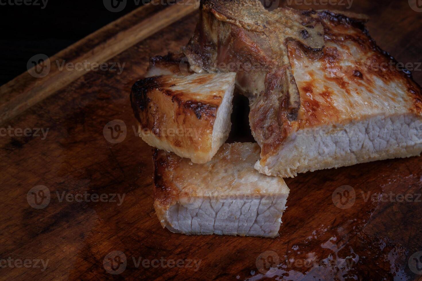 Roasted pork entrecote cut into pieces on a wooden cutting board. Grilled pork entrecote. Pork steak. photo