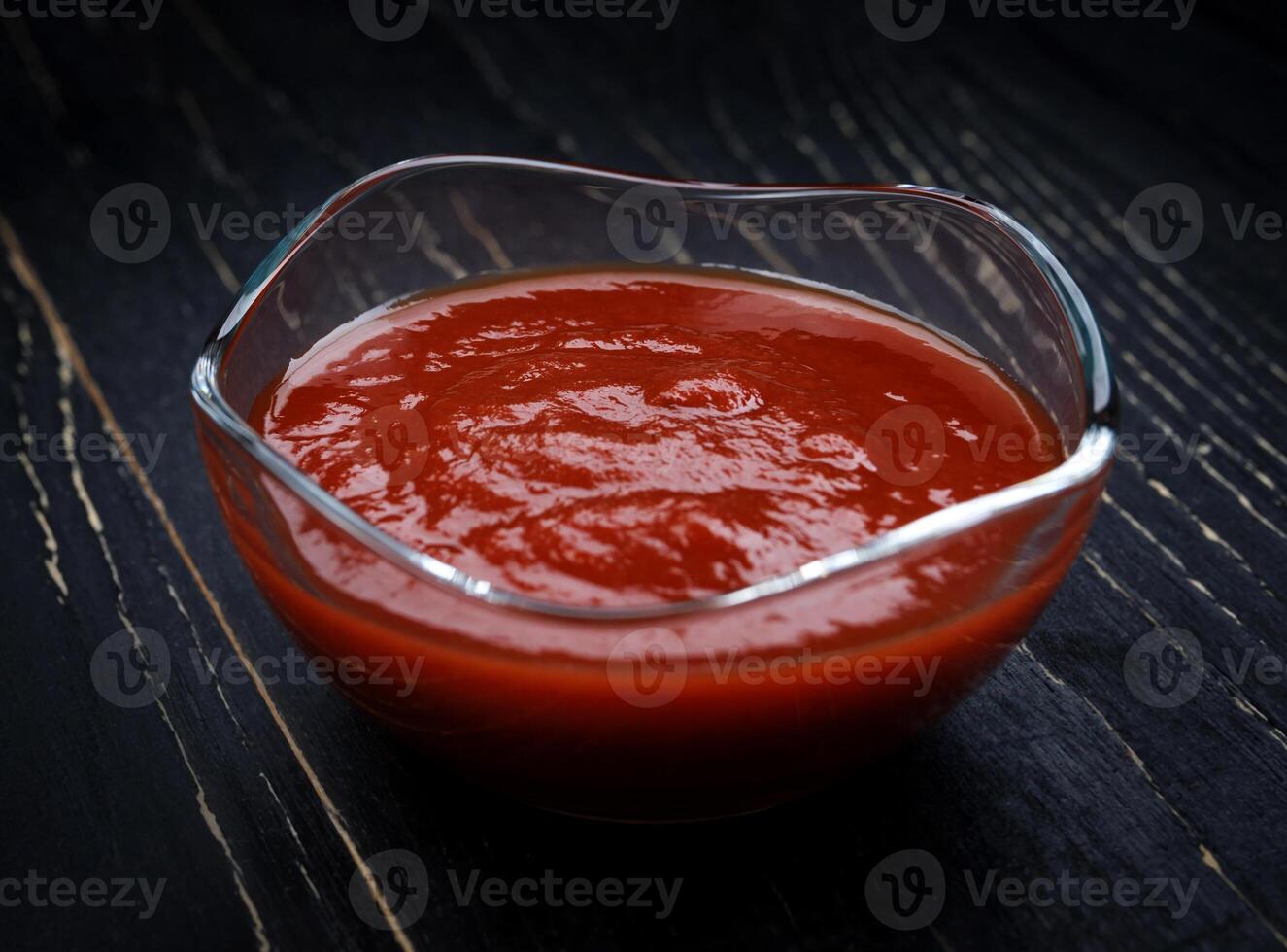 Ketchup in a glass cup on a black background. photo