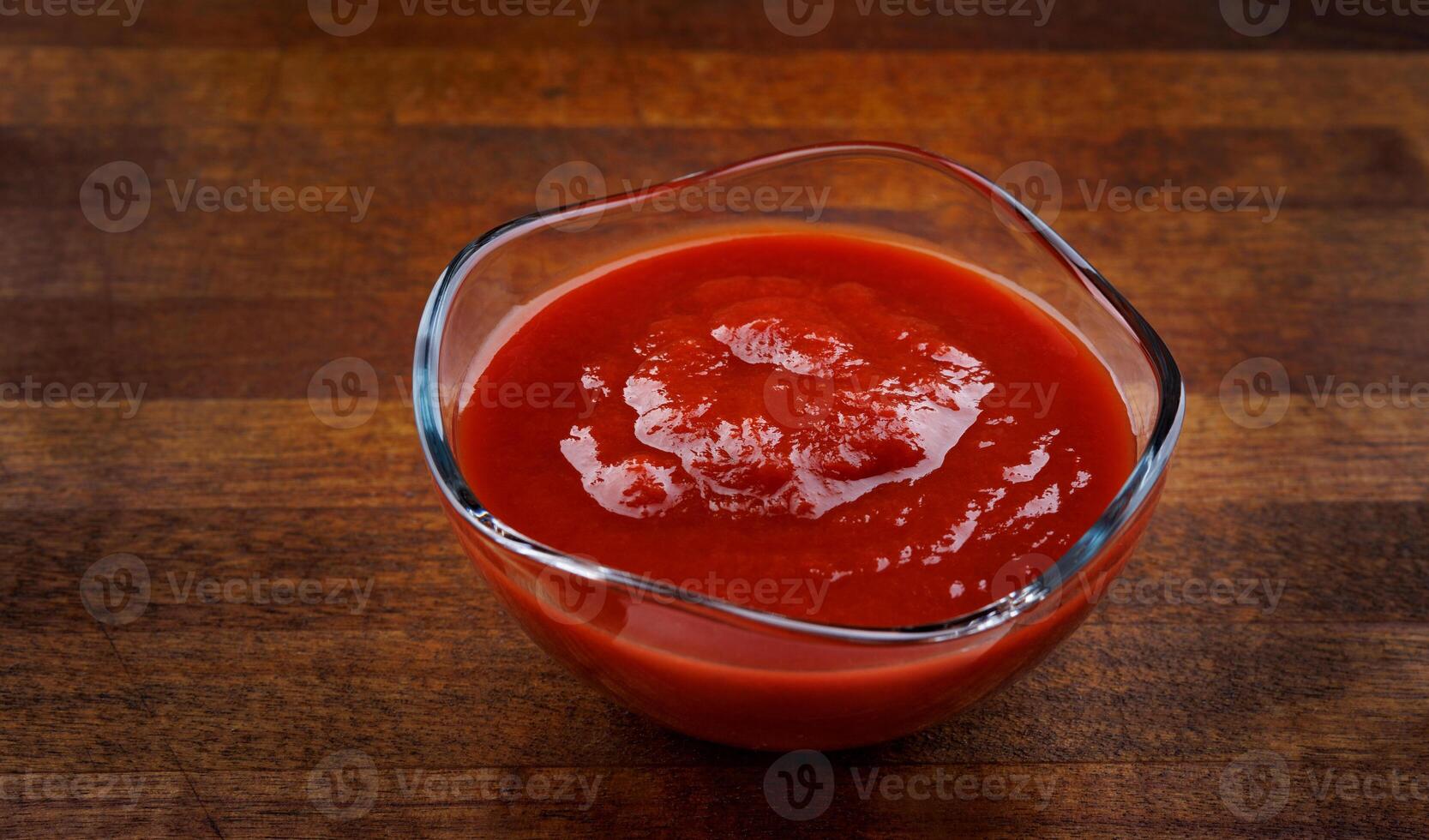 Ketchup in a glass cup on a wooden board. photo