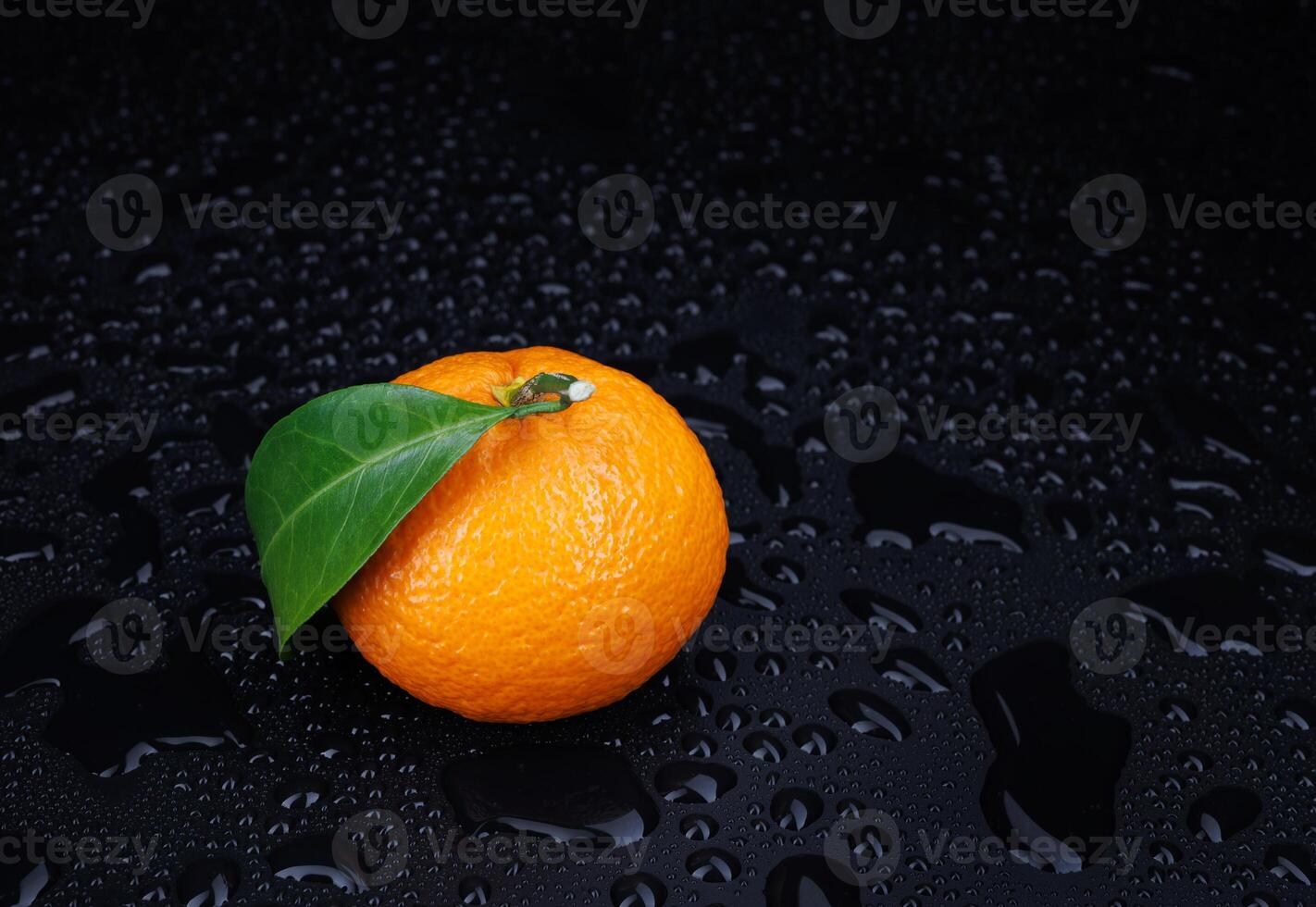 Ripe juicy tangerine on a black background with water drops. photo