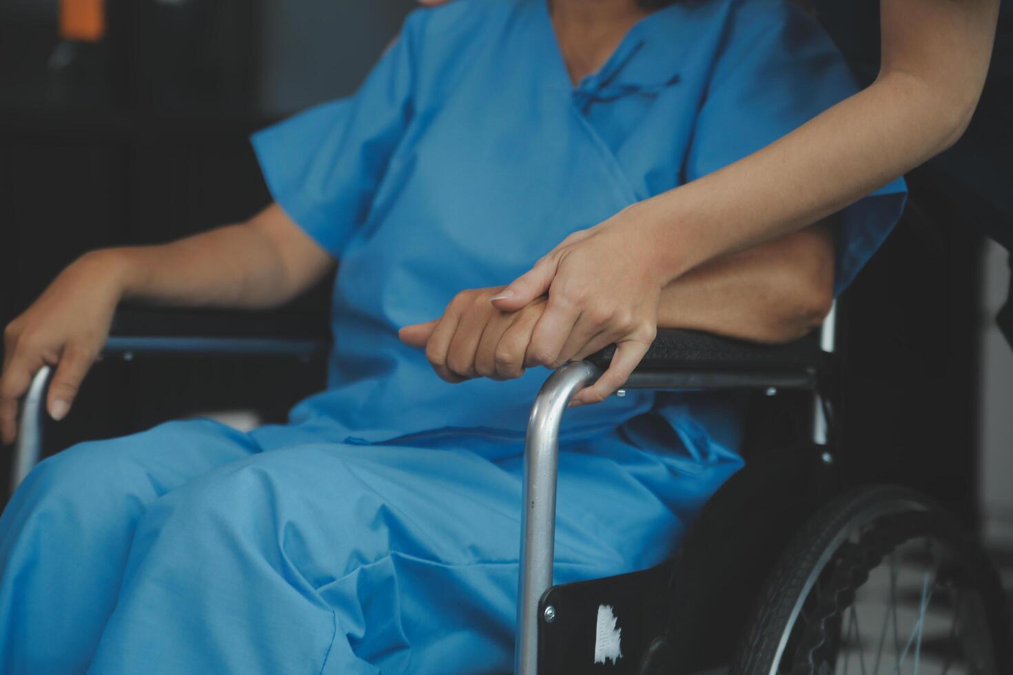 médico dando esperanza. cerca arriba Disparo de joven hembra médico propensión adelante a sonriente mayor dama paciente participación su mano en palmas mujer vigilante en blanco Saco secundario alentador antiguo persona foto