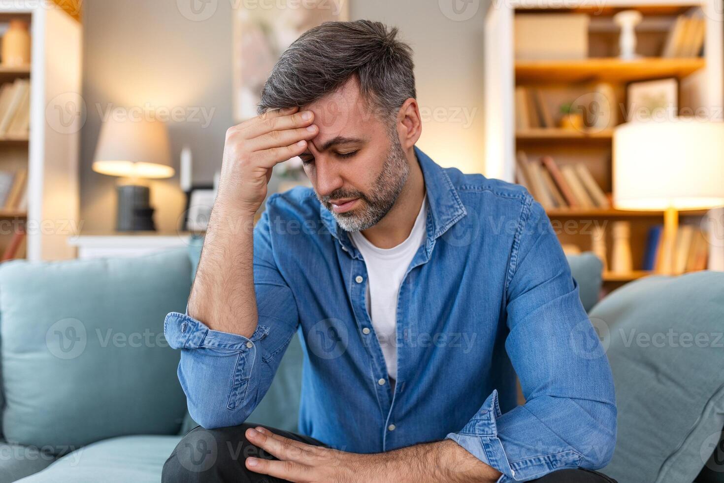 Closeup of man suffering from headache at home, touching his temples, copy space, blurred background. Migraine, headache, stress, tension problem, hangover concept photo