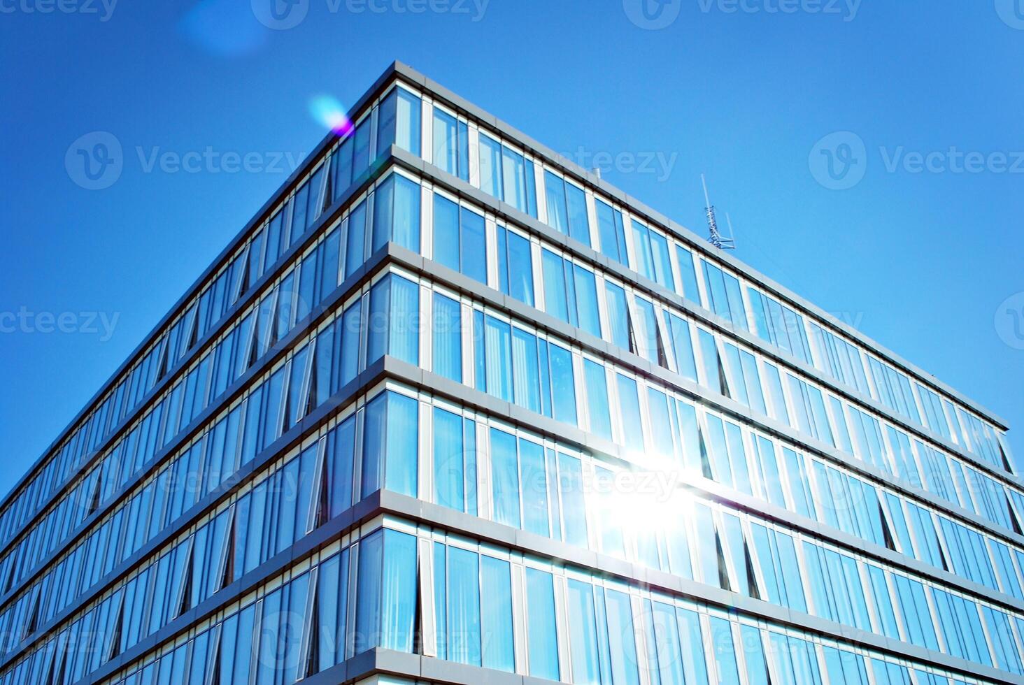 Glass building with transparent facade of the building and blue sky. Structural glass wall reflecting blue sky. Abstract modern architecture fragment. Contemporary architectural background. photo