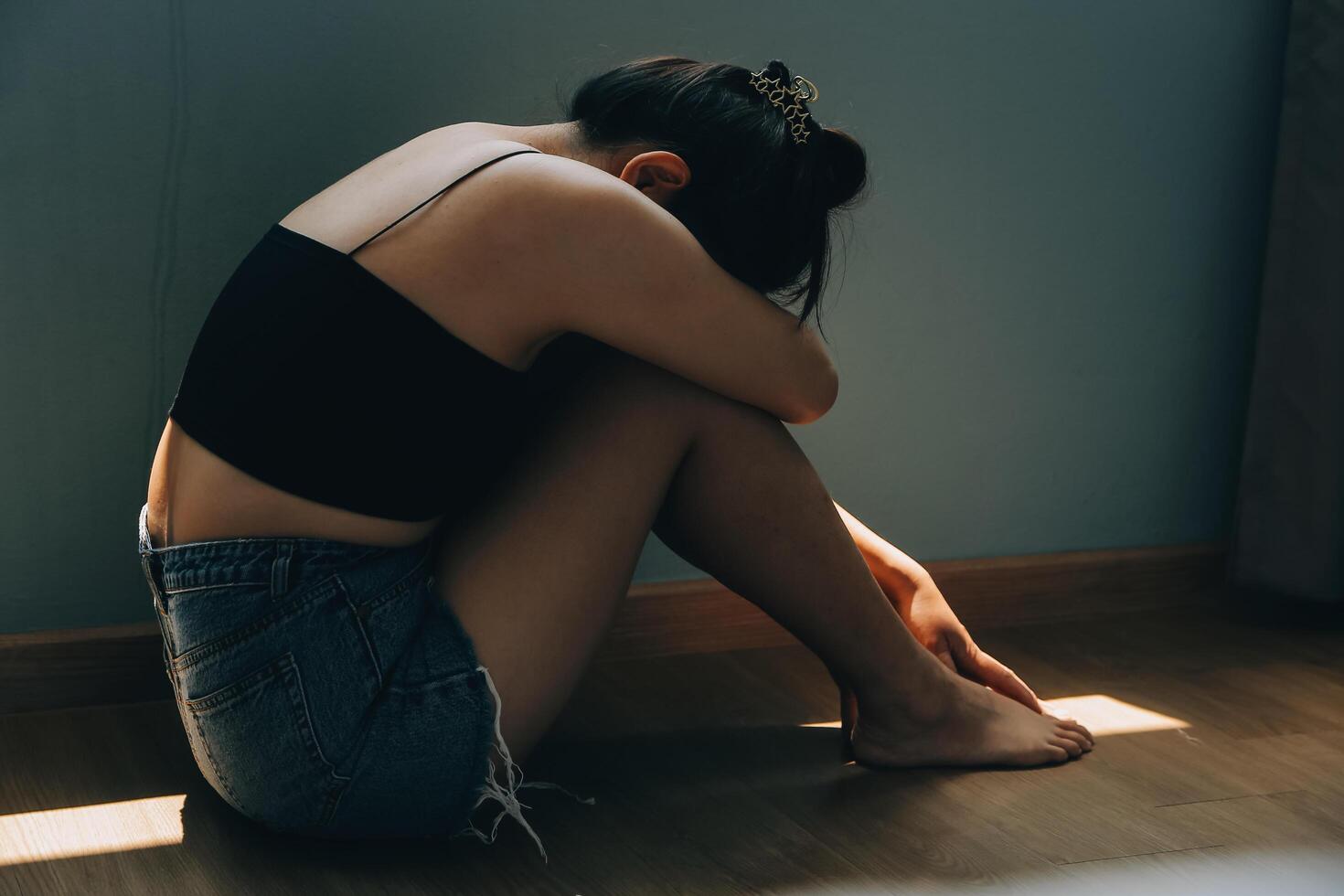 Thoughtful girl sitting on sill embracing knees looking at window, sad depressed teenager spending time alone at home, young upset pensive woman feeling lonely or frustrated thinking about problems photo