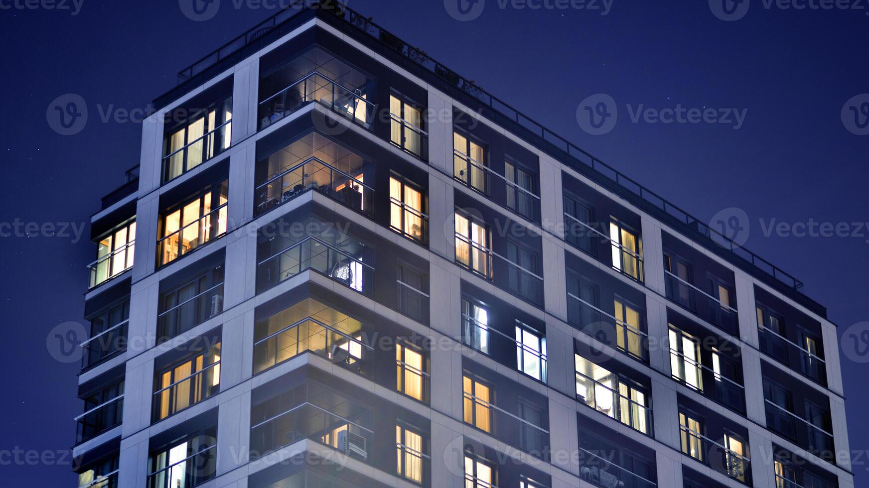 Glowing windows of the multi-storey building in night. View of modern residential building in downtown. photo