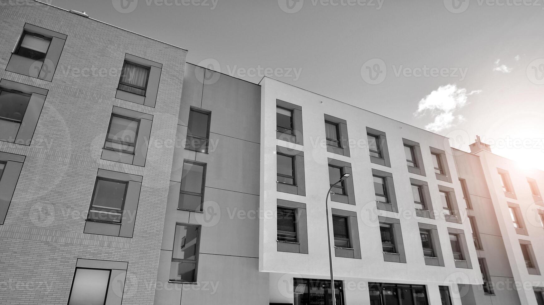 Fragment of the building's facade with windows and balconies. Modern apartment buildings on a sunny day. Facade of a modern residential building. Black and white. photo