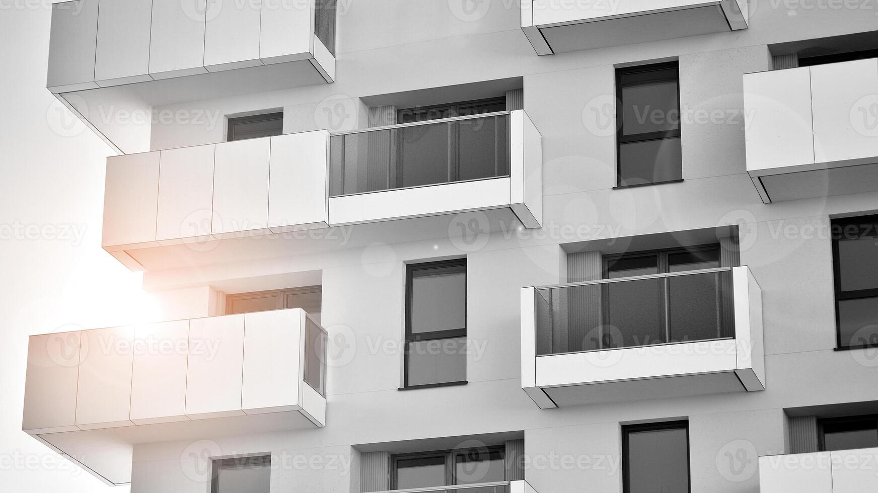 Fragment of the building's facade with windows and balconies. Modern apartment buildings on a sunny day. Facade of a modern residential building. Black and white. photo
