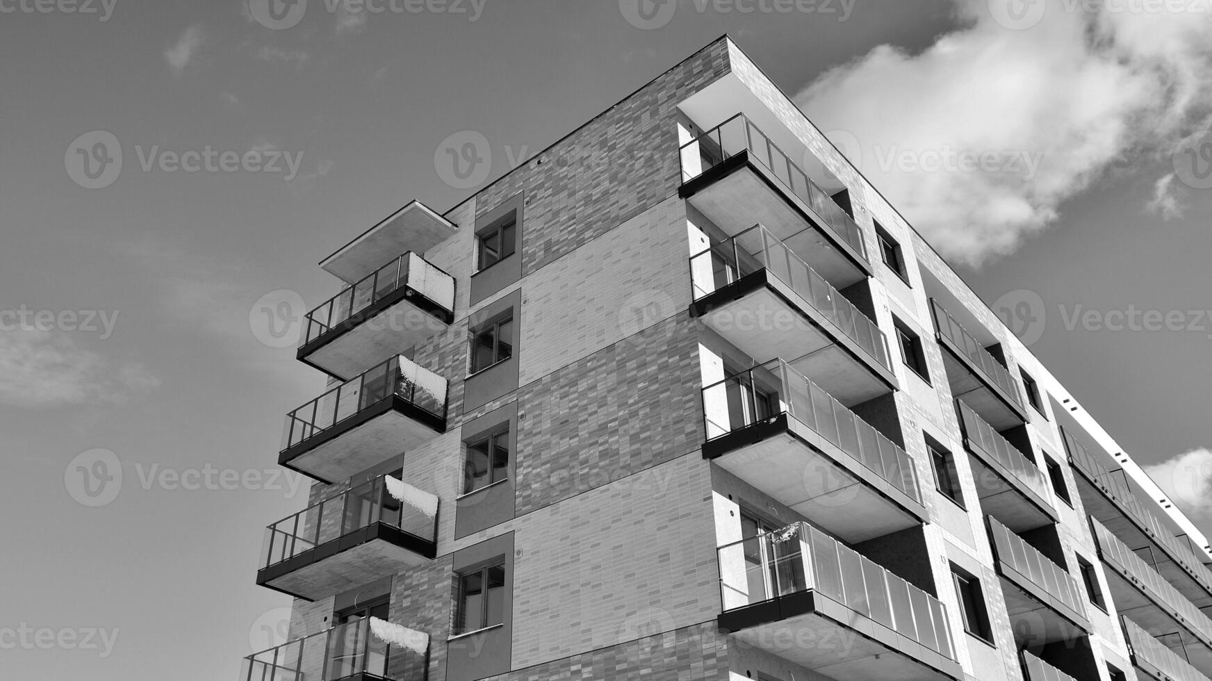 Fragment of the building's facade with windows and balconies. Modern apartment buildings on a sunny day. Facade of a modern residential building. Black and white. photo