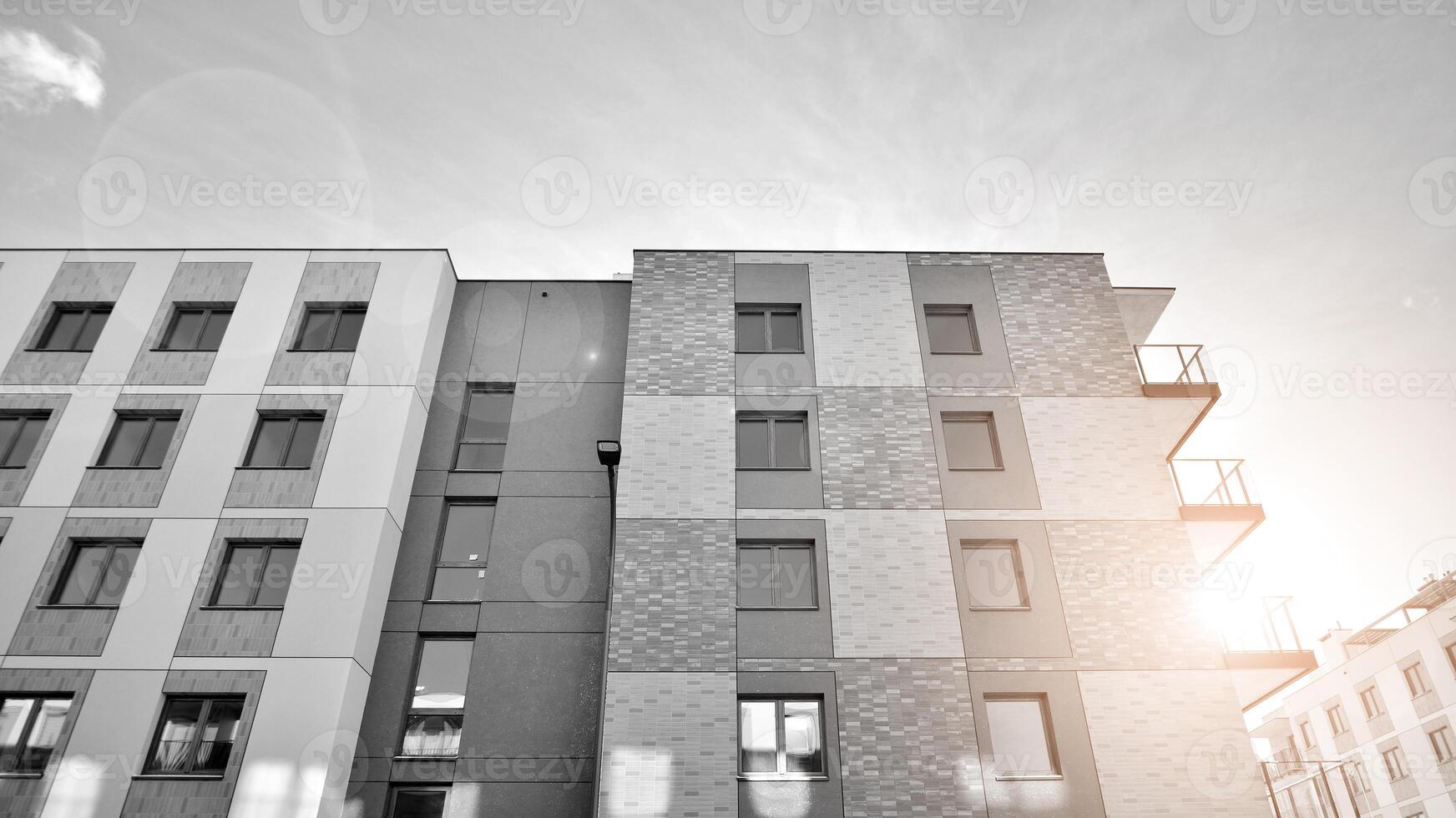 Fragment of the building's facade with windows and balconies. Modern apartment buildings on a sunny day. Facade of a modern residential building. Black and white. photo