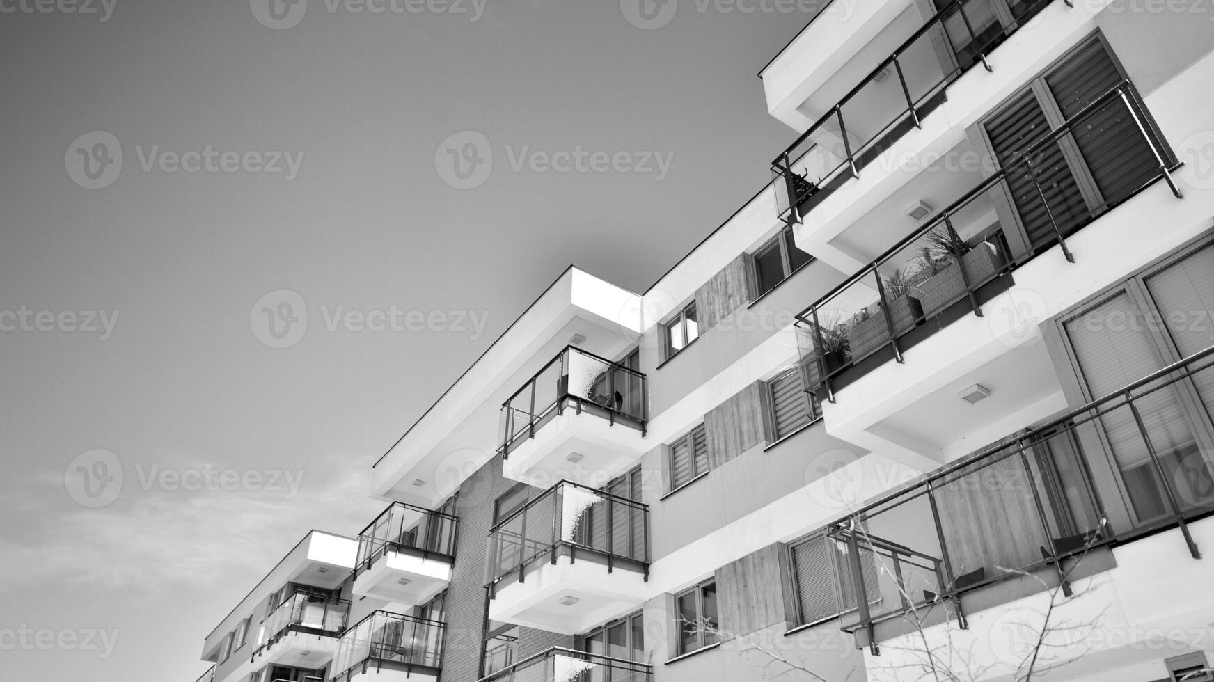Fragment of the building's facade with windows and balconies. Modern apartment buildings on a sunny day. Facade of a modern residential building. Black and white. photo