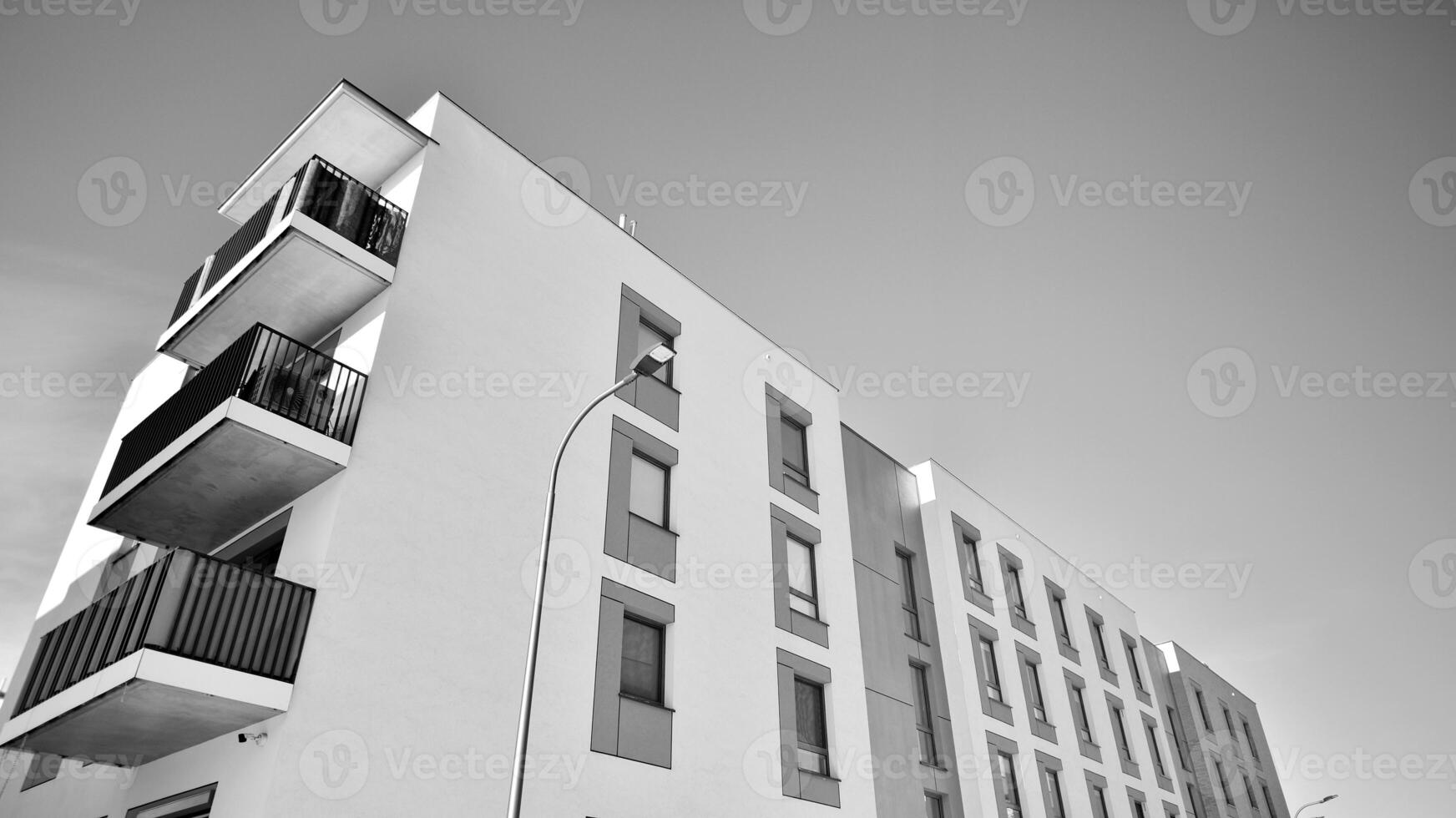 Fragment of the building's facade with windows and balconies. Modern apartment buildings on a sunny day. Facade of a modern residential building. Black and white. photo