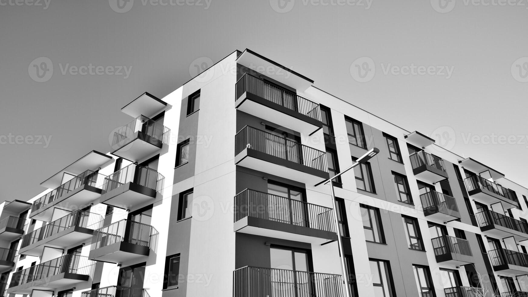Fragment of the building's facade with windows and balconies. Modern apartment buildings on a sunny day. Facade of a modern residential building. Black and white. photo
