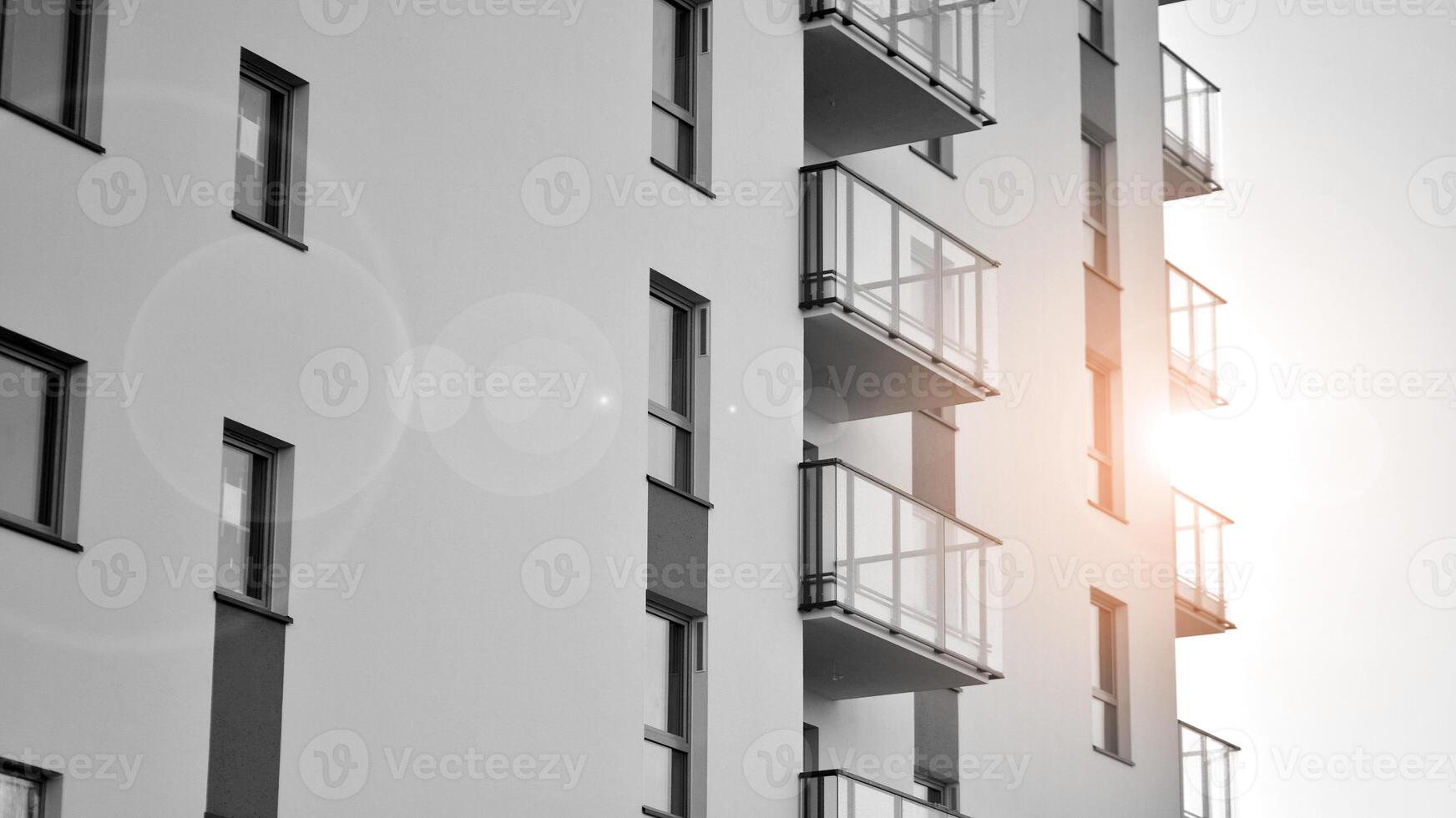 Fragment of the building's facade with windows and balconies. Modern apartment buildings on a sunny day. Facade of a modern residential building. Black and white. photo