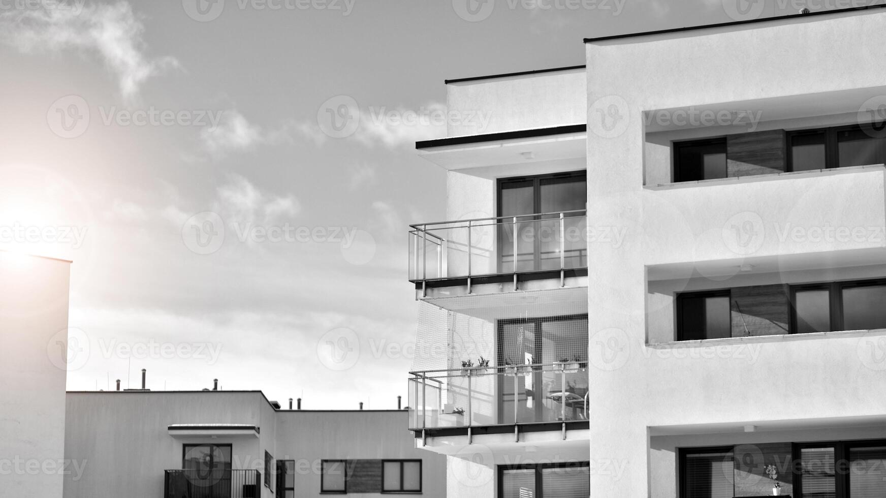 Fragment of the building's facade with windows and balconies. Modern apartment buildings on a sunny day. Facade of a modern residential building. Black and white. photo