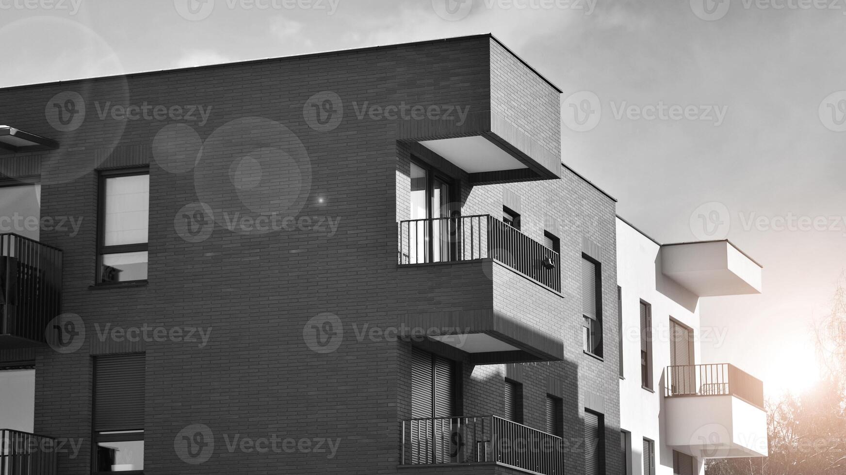 Fragment of the building's facade with windows and balconies. Modern apartment buildings on a sunny day. Facade of a modern residential building. Black and white. photo