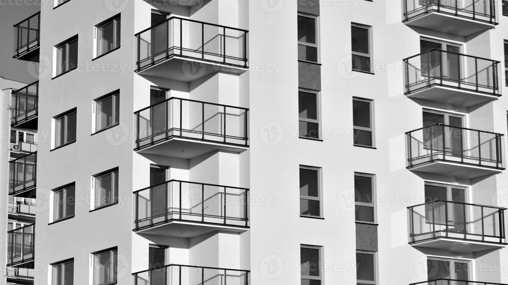 Fragment of the building's facade with windows and balconies. Modern apartment buildings on a sunny day. Facade of a modern residential building. Black and white. photo