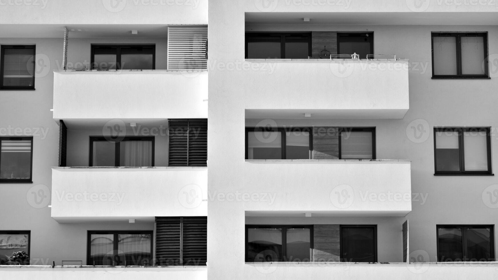 Fragment of the building's facade with windows and balconies. Modern apartment buildings on a sunny day. Facade of a modern residential building. Black and white. photo