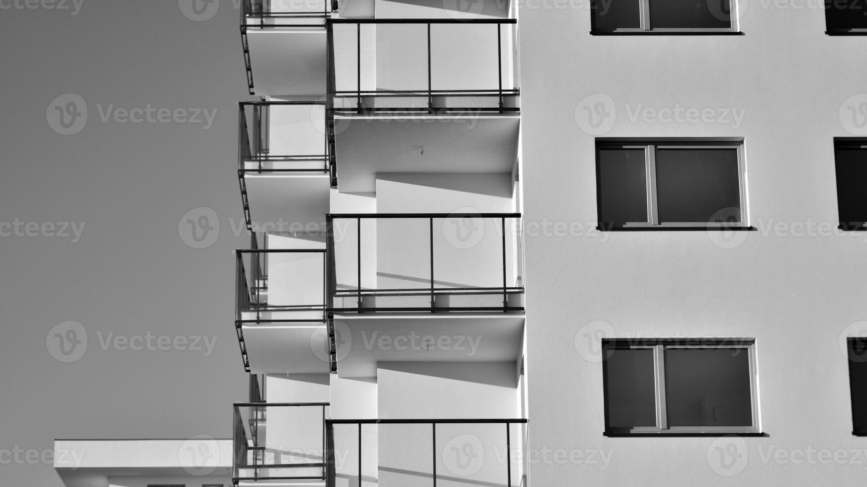 Fragment of the building's facade with windows and balconies. Modern apartment buildings on a sunny day. Facade of a modern residential building. Black and white. photo